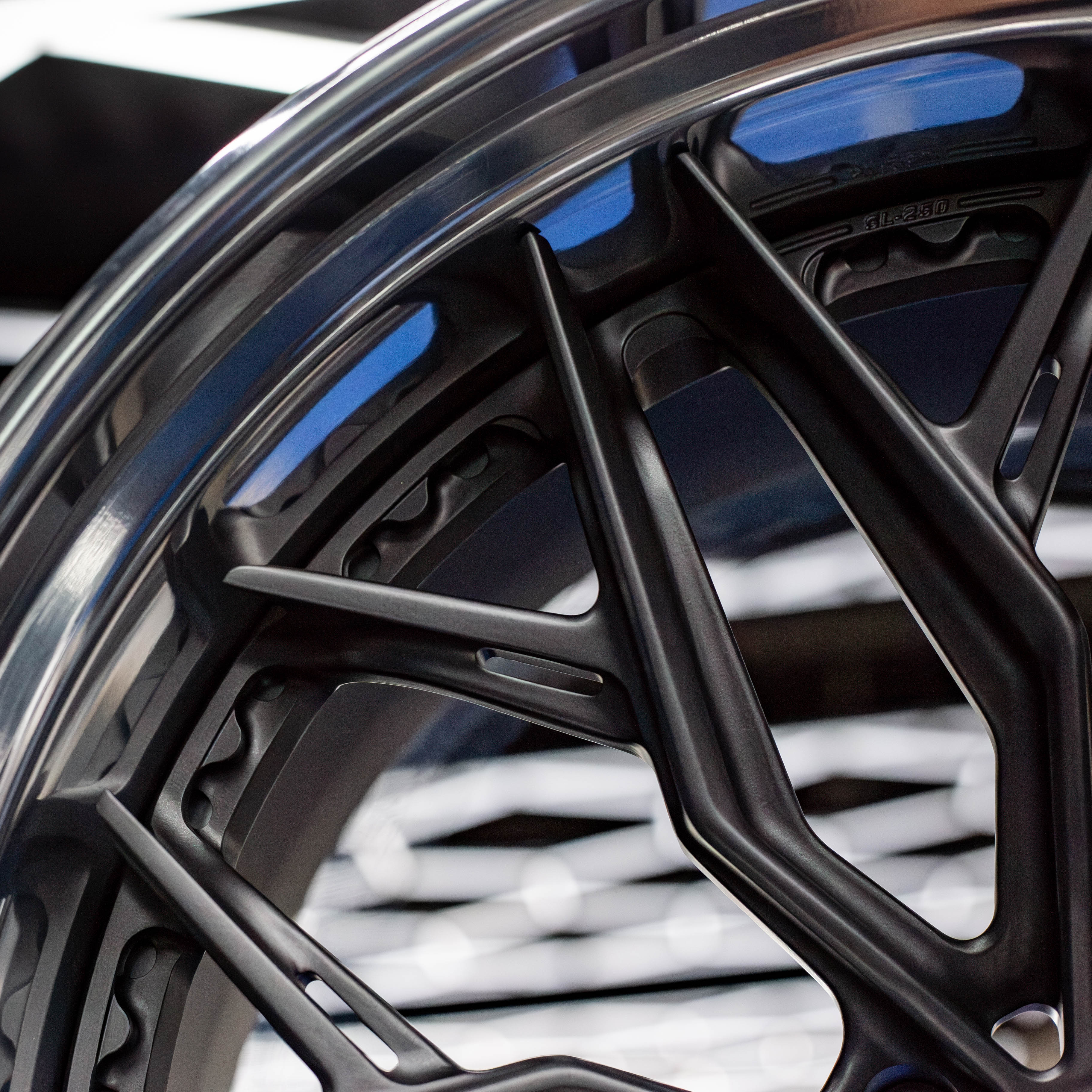 A black multi-spoke car wheel rim displayed on cardboard boxes.