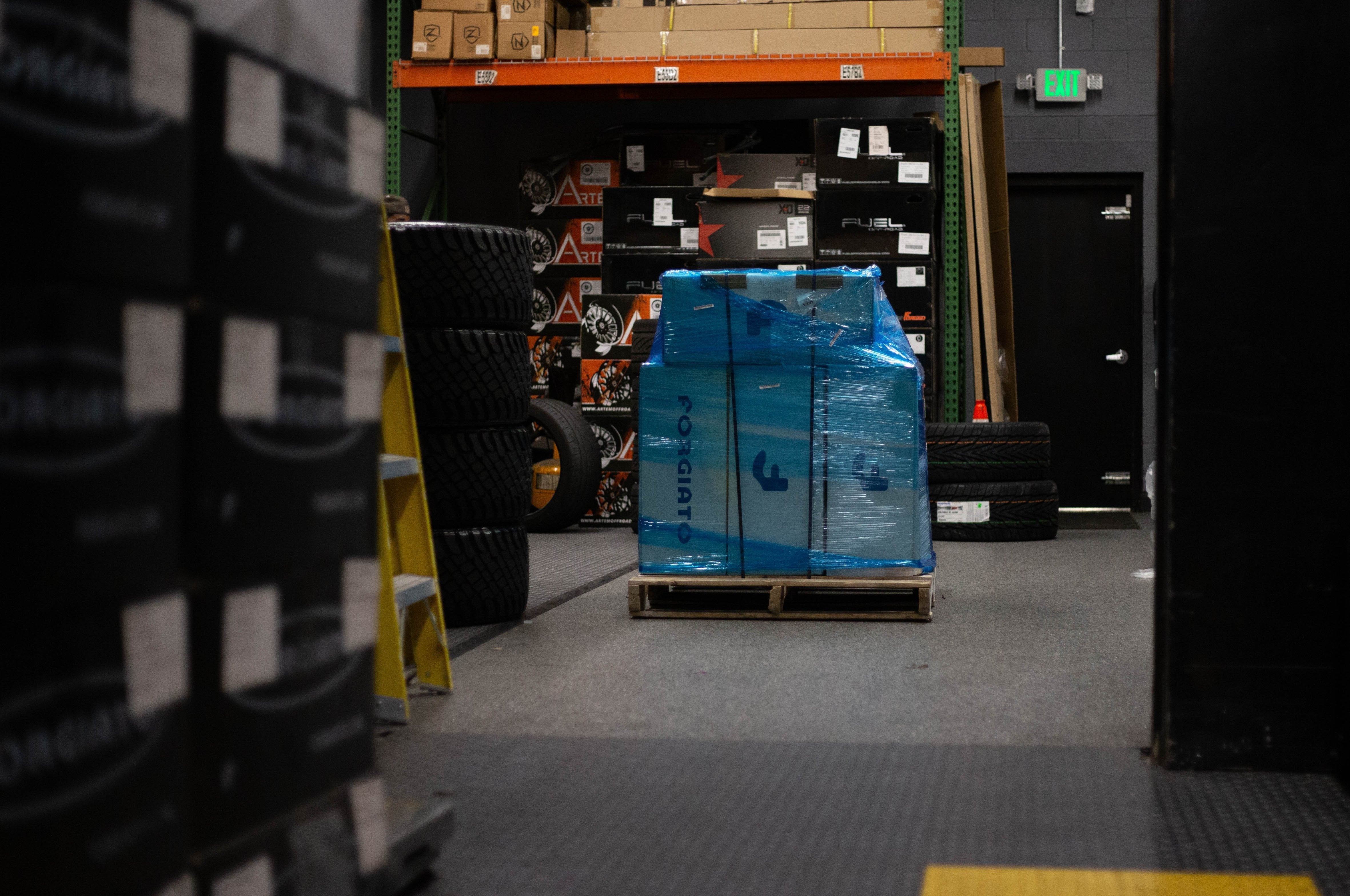 A black multi-spoke car wheel rim displayed on cardboard boxes.