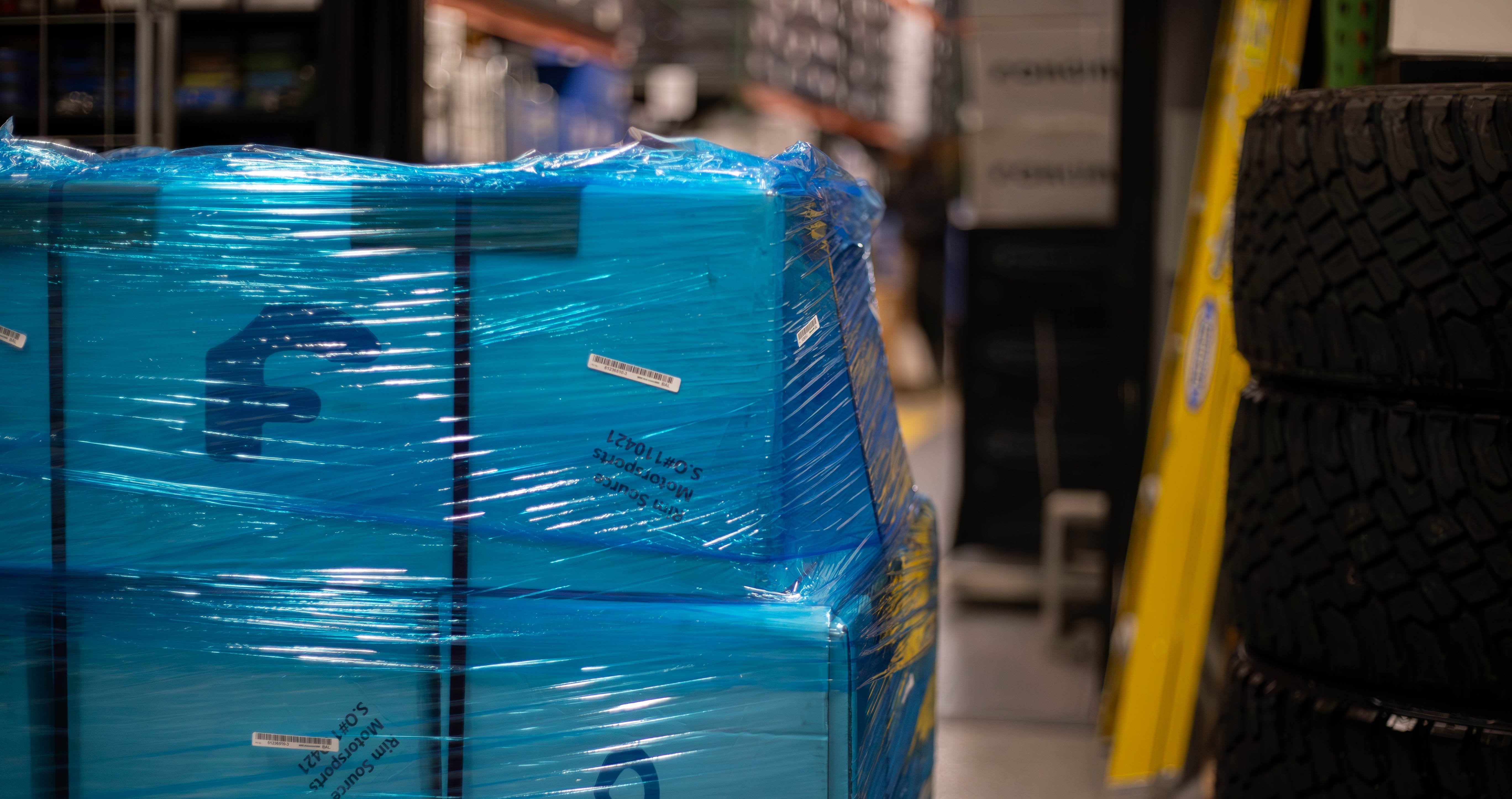 A black multi-spoke car wheel rim displayed on cardboard boxes.